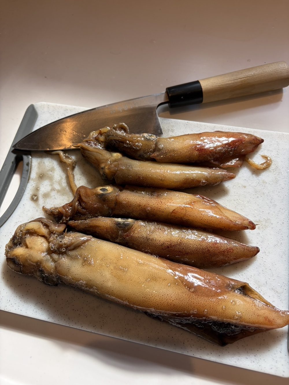 まな板に並べた釣ってきたケンサキイカと出刃包丁